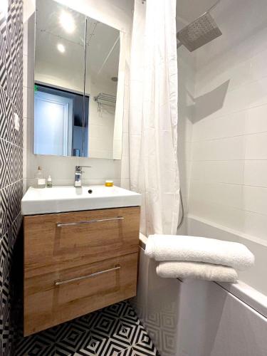 une salle de bain avec un lavabo, une baignoire et un miroir dans l'établissement L'appartement Michel-Ange, à Paris