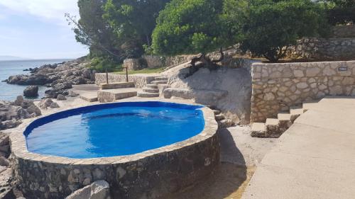 a swimming pool with a stone wall and the ocean at Apartments Anica Beber in Borovići