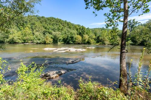 a river with rocks in the water and trees at Asheville River Cabins in Arden