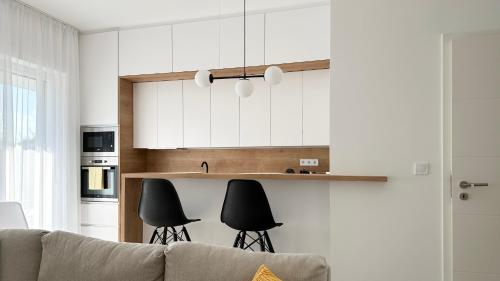 a kitchen with a couch and some black chairs at Linden Apartman 105 - Adults Only in Mosonmagyaróvár