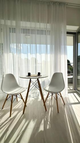 two chairs and a table in front of a window at Linden Apartman 105 - Adults Only in Mosonmagyaróvár