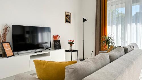 a living room with a couch and a flat screen tv at Linden Apartman 105 - Adults Only in Mosonmagyaróvár