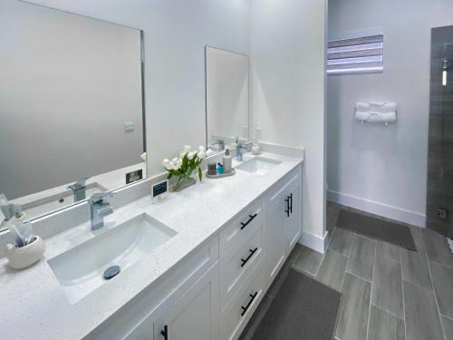 a white bathroom with a sink and a mirror at Corallo House - Heated Pool in Cape Coral