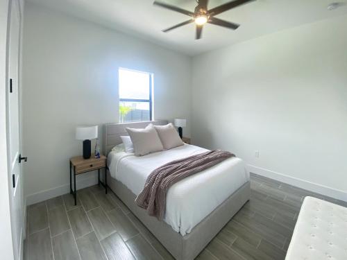 a white bedroom with a bed and a ceiling fan at Corallo House - Heated Pool in Cape Coral