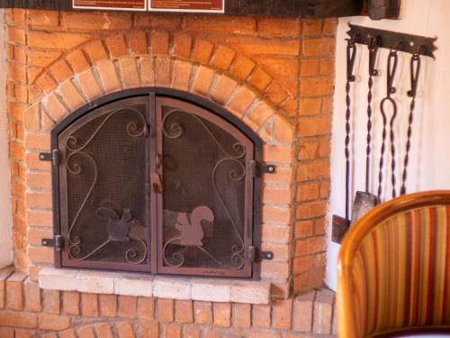 a brick fireplace with a door with animals on it at Pousada Suiça Mineira Centro in Monte Verde