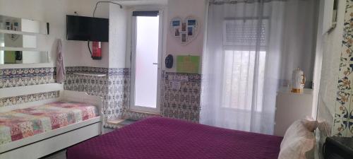a bedroom with a purple bed and a window at Apartamento Cavaleiro in Nazaré