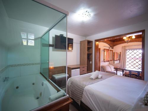 a bedroom with a tub and a bed and a bed and a television at Pousada Suiça Mineira Centro in Monte Verde