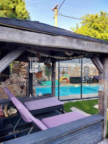 a wooden pergola with a lounge chair and a swimming pool at Aspen in Kamenný Újezd