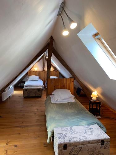 une chambre mansardée avec deux lits dans un grenier dans l'établissement La maison du Bec en Normandie, au Bec-Hellouin