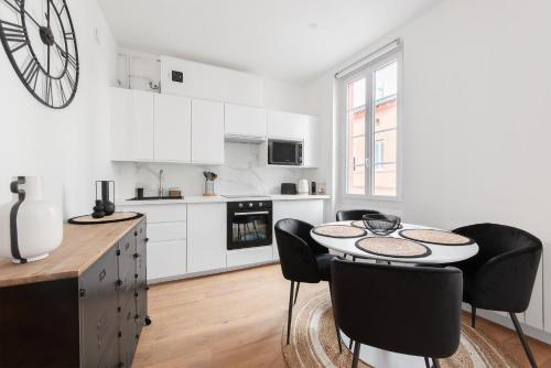 une cuisine avec des armoires blanches et une table et des chaises dans l'établissement Appartement moderne à 2 pas de la Gare, à Toulouse