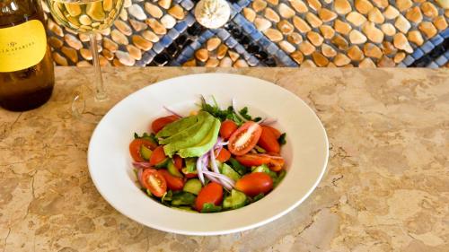 a bowl of salad on a table with a wine glass at The Villa Casa Casuarina in Miami Beach
