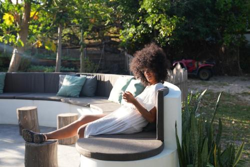 a woman sitting on a couch looking at her cell phone at La Ferme De Georges in Atins