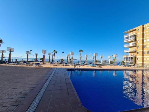 een zwembad naast een strand met palmbomen en een gebouw bij Apartamento Edificio Santa Margarita in Benidorm