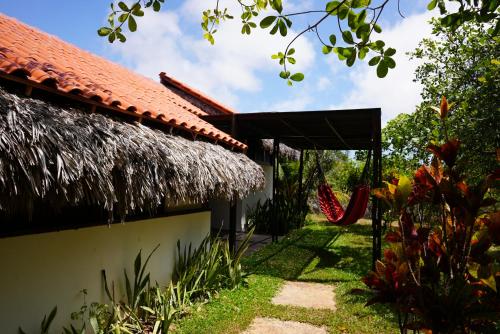 a house with a thatched roof and a swing at La Ferme De Georges in Atins