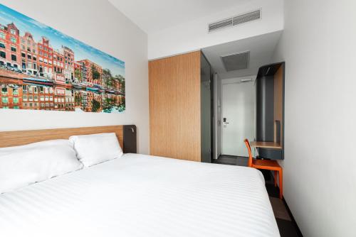 1 dormitorio con 1 cama y una pintura en la pared en easyHotel Amsterdam Arena Boulevard, en Ámsterdam