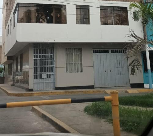 un edificio blanco con una palmera delante en Habitación 2 camas a pasos del Aeropuerto Lima, en Lima