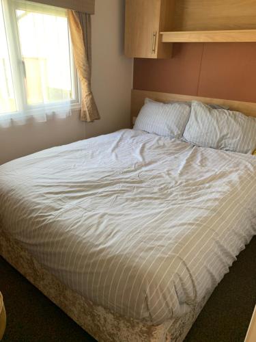 uma grande cama branca num quarto com uma janela em 8 Birth Caravan Marine Holiday Park Rhyl em Rhyl