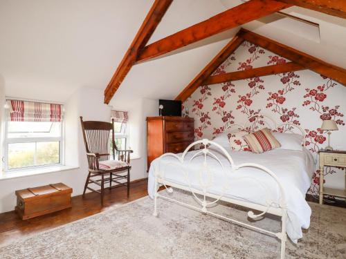 a bedroom with a white bed and a chair at Quiet Trees in Bodmin