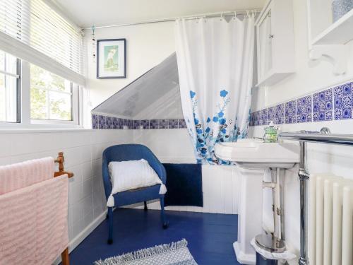 ein Badezimmer mit einem Waschbecken und einem blauen Stuhl in der Unterkunft Quiet Trees in Bodmin