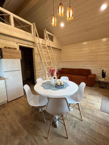 a dining room with a white table and chairs at Milkės Karibai - poilsio namelis su sauna ir kubilu in Statiškė