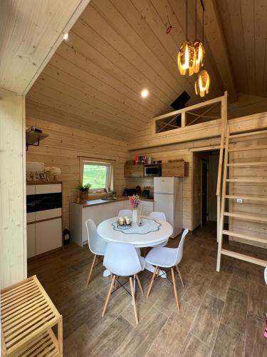 a kitchen and dining room of a tiny house with a table and chairs at Milkės Karibai - poilsio namelis su sauna ir kubilu 