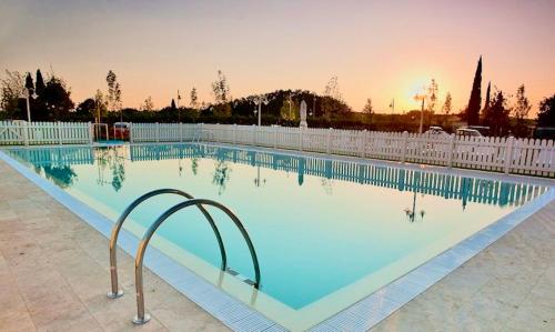 タヴァルネッレ・ヴァル・ディ・ペーザにあるResidence with swimming-pool in Barberino Tavernelleのフェンス付きの大型スイミングプール、夕日を望む