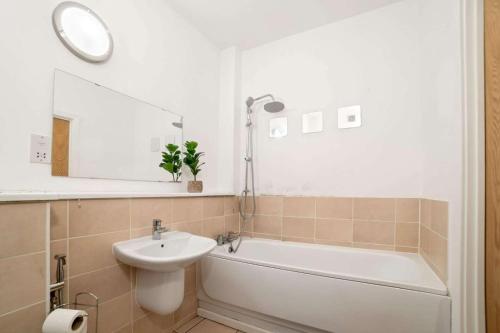 ein Badezimmer mit einem Waschbecken, einer Badewanne und einem Spiegel in der Unterkunft Spacious City Centre Apartment w/ Free Valet Parking in Leicester