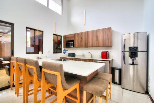 a kitchen with a large island with chairs and a refrigerator at Natural Arenas 47 ! in Herradura