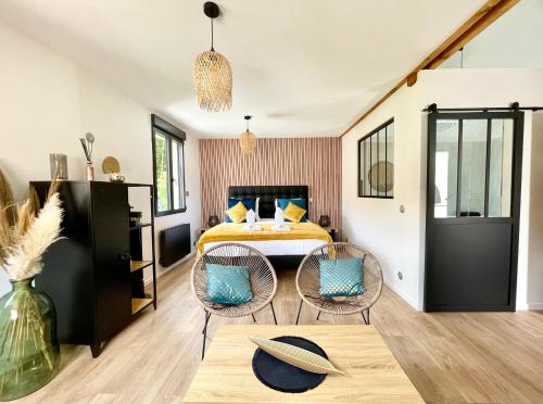 une chambre avec un lit, deux chaises et une table dans l'établissement L’escapade romantique - Chambre moderne Jaccuzi, à Guermantes