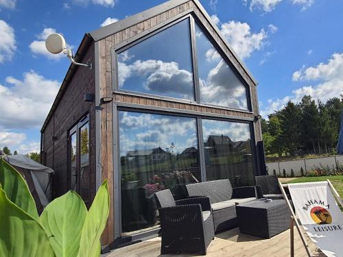 a tiny house with a lot of glass at Domek mazurski całoroczny nad jeziorem z Sauną fińską I Jacuzzi SPA in Pasym