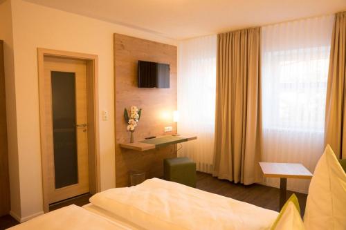a hotel room with a bed and a desk and a window at Gasthaus Schwarzer Adler in Colmberg