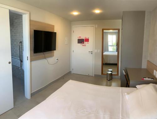 a bedroom with a bed and a tv on a wall at Liiv Mar - Natal Ponta Negra in Natal