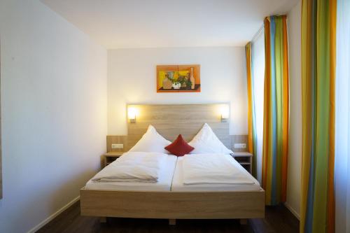 1 dormitorio con 1 cama con sábanas blancas y almohadas rojas en Gasthaus Schwarzer Adler, en Colmberg