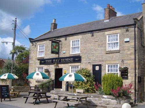 a pub with tables and umbrellas in front of it at The Bay Horse Country Inn in Thirsk