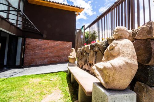 a stone statue sitting on a bench in front of a building at Hacienda del Valle Sagrado in Urubamba