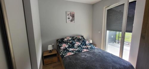 Schlafzimmer mit einem Bett mit einem Kissen und einem Fenster in der Unterkunft Apartament Bursztyn in Jantar