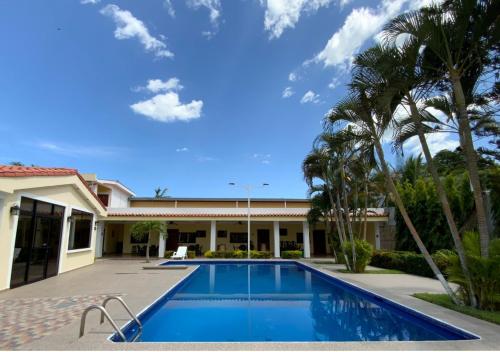 a swimming pool in front of a house with palm trees at Hotel y Restaurante Maria Ofelia in San Luis