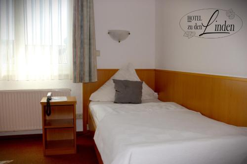 a small bedroom with two beds and a night stand at Hotel zu den Linden in Wachtberg