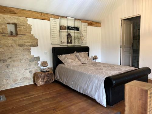 a bedroom with a large bed and a stone wall at Gîte Chez Père Thomas pour 2-3 pers in Champagne-Mouton