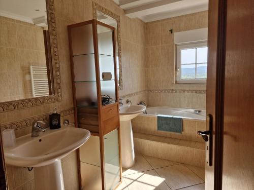 Villa Monte Branco في ساو بارتولوميو دي ميسينيس: حمام به مغسلتين وحوض استحمام ومرآة