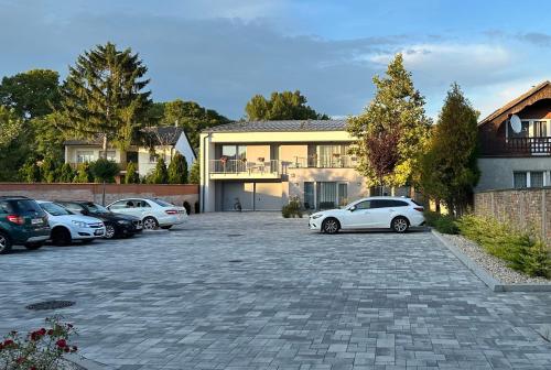 a parking lot with cars parked in front of a house at Linden Apartman 106 - Adults Only in Mosonmagyaróvár