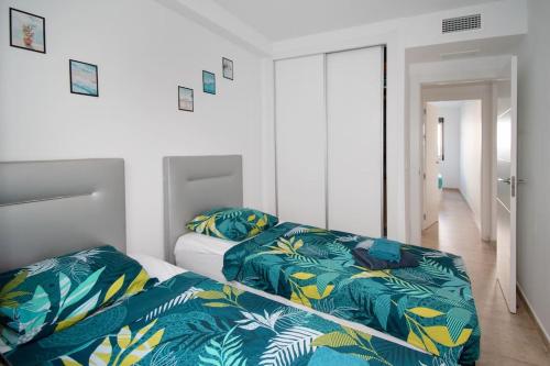 a bedroom with two beds with blue and yellow blankets at Torrebeach in Torre de la Horadada