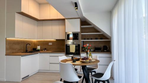 a kitchen with white cabinets and a table and chairs at Linden Apartman 106 - Adults Only in Mosonmagyaróvár