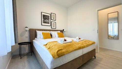 a bedroom with a large bed with yellow pillows at Linden Apartman 106 - Adults Only in Mosonmagyaróvár