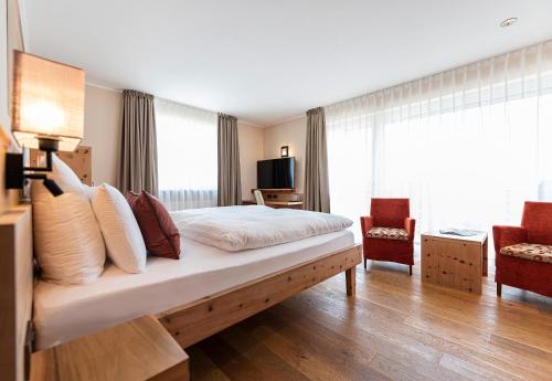 a hotel room with a bed and a living room at Vitalpina Hotel Waldhof in Rablà