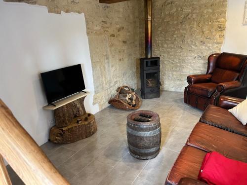 a living room with a tv and a wood stove at Gîte Chez Père Thomas pour 2-3 pers in Champagne-Mouton