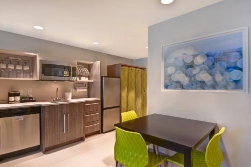 a kitchen with a black table and yellow chairs at Home2 Suites By Hilton Naples I-75 Pine Ridge Road in Naples
