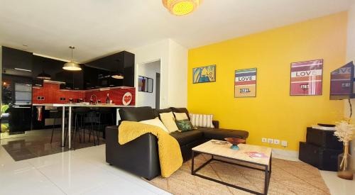 sala de estar con sofá negro y pared amarilla en Happy Stay Disney Two - Apartment with garden & parking, en Montévrain