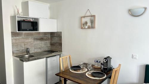 une petite cuisine avec une table et un micro-ondes dans l'établissement Le Bussy - Chambre double Disney, à Bussy-Saint-Georges