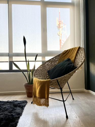 a wicker chair in a room with a window at Bello y luminoso apatamento en el Centro Historico in Mexico City